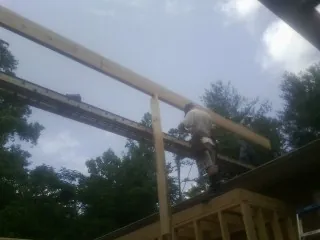 Carpenter setting a ridge beam over a new addition frame — Ice Dam Removal by Roofing Brothers in Church View