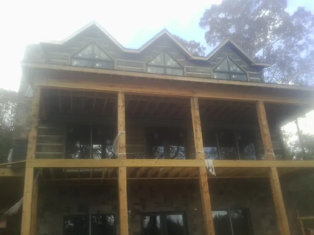 Dormers and porch framing on a large log home under construction — Roof Coating work by our crew in Church View