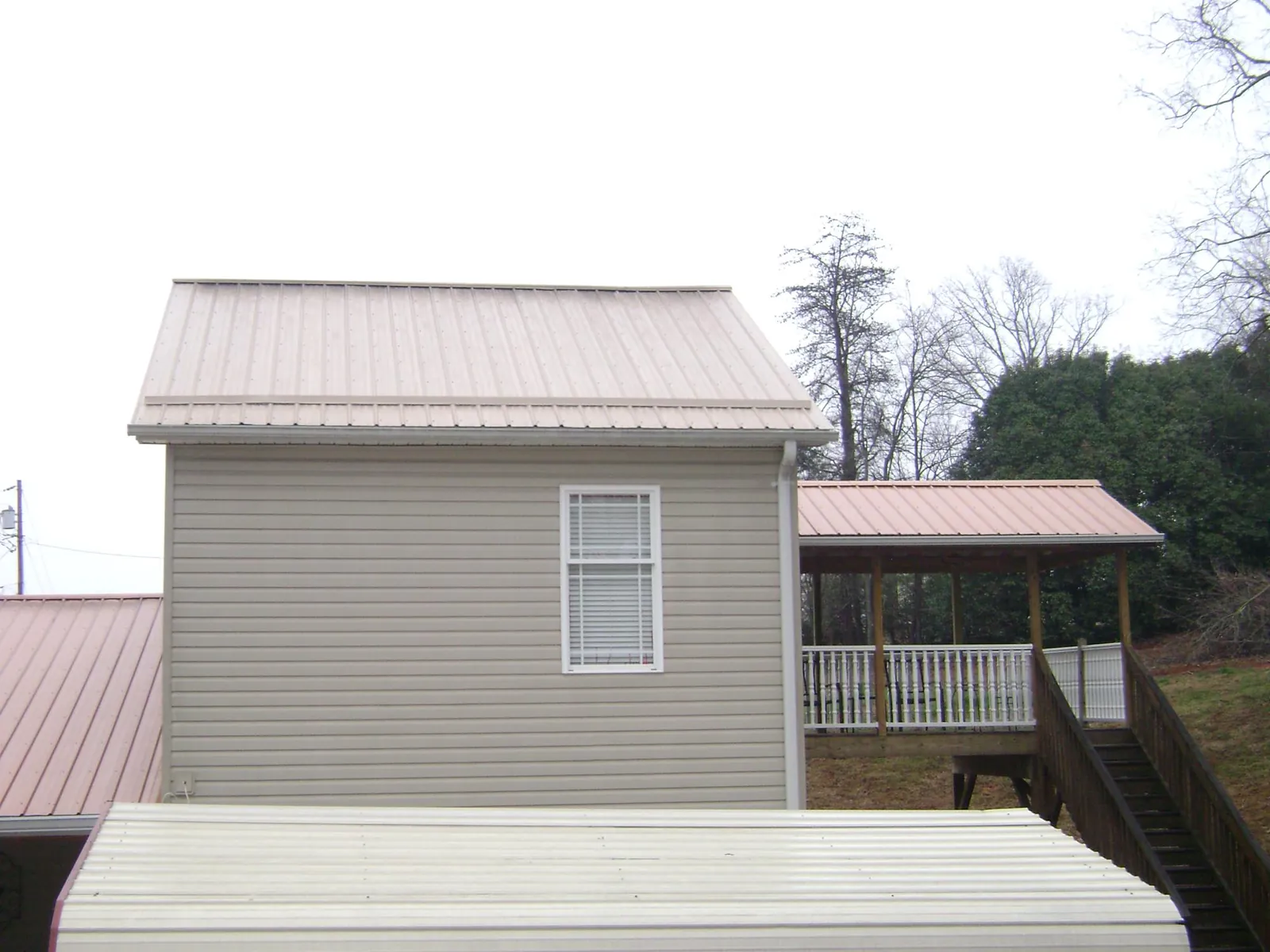 Tan metal roofs on a two story addition and attached porch, from a Roof Replacement job in Church View