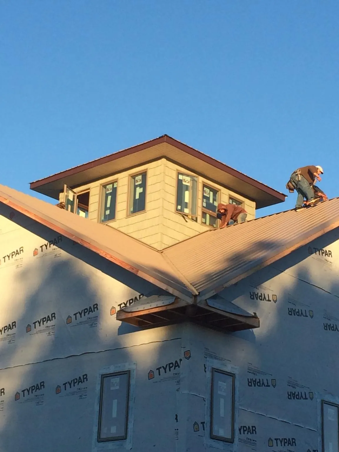 Roofers working around a rooftop cupola on a new metal roof at sunset — Roof Waterproofing in Church View by Roofing Brothers